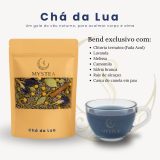 Pacote de chá Mystea “Chá da Lua” ao lado de uma xícara transparente com infusão azul e uma lista dos ingredientes do blend exclusivo, sobre fundo claro com detalhes gráficos.