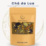 Pacote dourado de chá Mystea rotulado como “Chá da Lua”, contendo mistura de lavanda, camomila, folhas e especiarias visíveis na janela transparente, com o texto “Um gole do céu noturno, para acalmar corpo e alma”.