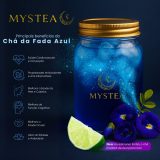 Pote azul brilhante de Chá da Fada Azul Mystea com gelo e partículas luminosas, ao lado de flores de Clitoria ternatea e uma fatia de limão, com lista dos principais benefícios do chá.