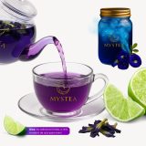 Chaleira transparente despejando chá roxo Mystic Mystea em uma xícara de vidro, com limões ao redor e um pote azul ao fundo; flores de Clitoria ternatea ilustram a mudança de cor do chá ao adicionar limão.