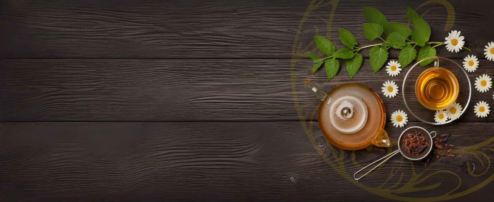 Mesa de madeira escura com bule de chá transparente, xícara de chá dourado, flores de camomila, folhas de hortelã e especiarias distribuídas ao lado direito da imagem.